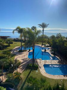 uma vista aérea de uma piscina com palmeiras e do oceano em ARRUZAFA PLAYA Beachfront apartment La Cala de Mijas em La Cala de Mijas