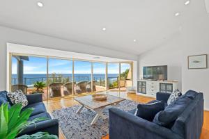 a living room with blue couches and a table at Spacious Home with Ocean Views, Close to Beach in Wamberal