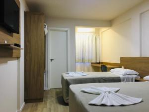 um quarto de hotel com duas camas e uma televisão em Hotel Paris em Curitibanos