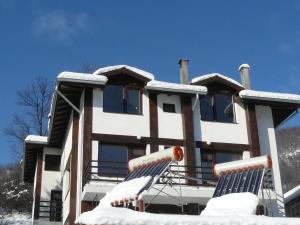 a building covered in snow with two lounge chairs at House Arirang in Cherni Osŭm +8 photos