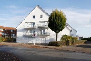 una casa blanca con un árbol al lado de una calle en Lieblingshafen, en Grömitz
