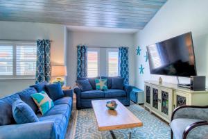a living room with blue couches and a flat screen tv at Flip Flops & Pop Tops in Port Aransas