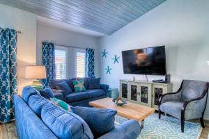 a living room with blue furniture and a flat screen tv at Flip Flops & Pop Tops in Port Aransas