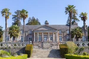 an old mansion with palm trees and stairs at Camping de l'Orangerie de Lanniron in Quimper