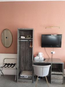 een kamer met een bureau en een tv aan de muur bij Alexander Guest House in Edinburgh