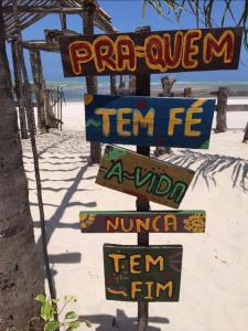 um sinal na praia com sinais na areia em Casa de Praia - tipo chalé em Barra de Santo Antônio