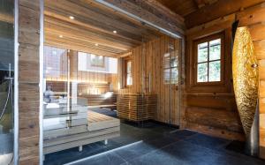 a sauna with wooden walls and a glass wall at Wellness Hotel Alpenhof in Zermatt
