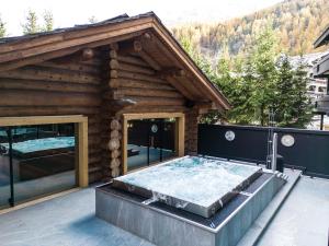 a hot tub in front of a log building at Wellness Hotel Alpenhof in Zermatt