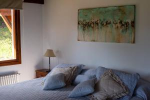 拉安戈斯圖拉鎮的住宿－Casa del Sur Villa La Angostura，卧室配有一张床,墙上挂有绘画作品