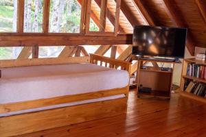 ein Schlafzimmer mit einem Bett und einem Flachbildfernseher in der Unterkunft Casa del Sur Villa La Angostura in Villa La Angostura