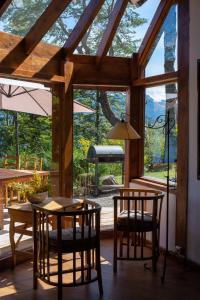 ein Raum mit Tisch und Stühlen und einem großen Fenster in der Unterkunft Casa del Sur Villa La Angostura in Villa La Angostura