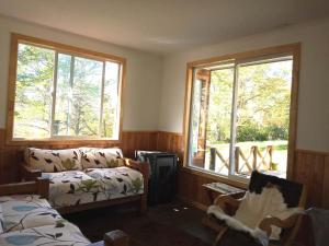 uma sala de estar com um sofá e duas janelas em Cabaña Turismo EL SUSURRO em Coihaique