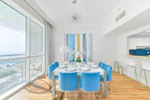 a dining room with a white table and blue chairs at Al Bateen · Ultra Luxury JBR · Private Beach and Pool in Dubai