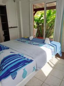 a bed with blue and white sheets and a window at Villa ensoleillée avec piscine privée à Saint-François in Saint-François