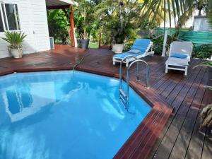 a swimming pool on a wooden deck with chairs and a swimming poolvisor at Villa ensoleillée avec piscine privée à Saint-François in Saint-François +15 photos