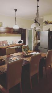 uma cozinha com uma mesa de madeira com cadeiras e uma cozinha com um frigorífico em Bella Garden em Balatonszárszó