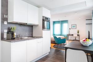 a kitchen with white cabinets and a dining room at SERVENTO Boardinghouse in Erlangen