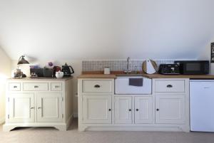 una cucina con armadi bianchi e lavastoviglie bianca di THE DEN, a Secluded Annex, Hot-tub, Heating & Breakfast a Long Bredy