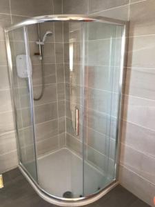 La salle de bains est pourvue d'une douche avec une porte en verre. dans l'établissement Milo's Cosy Cottage Giant's Causeway, à Bushmills