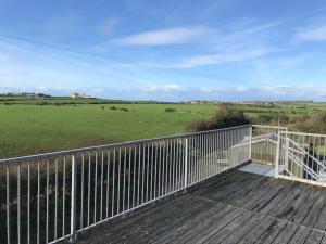 a deck with a view of a green field at Milo's Cosy Cottage Giant's Causeway in Bushmills