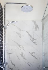 e bagno con doccia e pareti in marmo bianco. di THE DEN, a Secluded Annex, Hot-tub, Heating & Breakfast a Long Bredy