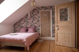 Cette chambre comprend un lit avec des draps roses et du parquet. dans l'établissement Le Parc du Magnolia, à Montbéliard