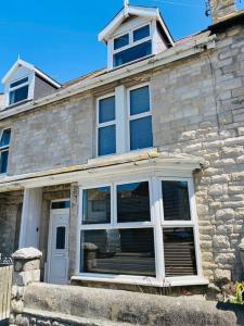 Casa de piedra con puerta blanca y ventanas en Chiswell Cottage a large family nr WPNSA & Beach, en Castletown