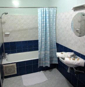 La salle de bains est pourvue de carrelage bleu, d'un lavabo et d'une douche. dans l'établissement Marrakech Hôtel Résidence, à Marrakech