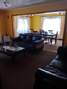 a living room with a black leather couch and a table at HOWENH in Porvenir +8 photos