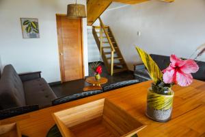 una mesa con un jarrón con una flor rosa dentro en Matariki Sunset Apart Hotel en Hanga Roa