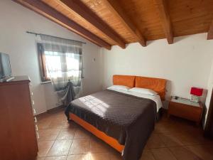 1 dormitorio con 1 cama con cabecero naranja y ventana en AURA l.t en Fiumicino