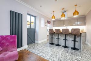 a kitchen with a bar and a pink couch at East Cottage * Wood Burning Hot Tub * Garden in St. Andrews