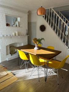 a dining room with a wooden table and yellow chairs at Sea Song Cottage in Broadstairs