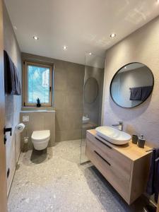 a bathroom with a sink and a toilet and a mirror at Apartment Aliprandi in See