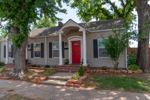 a house with a red door and a tree at The Cozy, Fiber Internet, Roku TVs, Washer & Dryer, Near DT Chickasha & Leg Lamp! in Chickasha