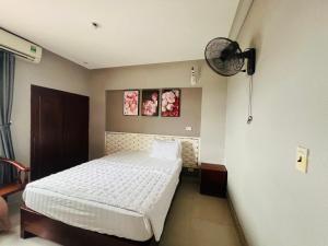Schlafzimmer mit einem weißen Bett und einem Ventilator in der Unterkunft Hoang Ngan 1 Hotel - TP. Vinh in Vinh