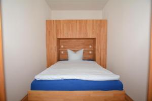 ボルクムにあるGaestehaus-Flandern-1のベッドルーム1室(白いシーツと木製ヘッドボード付きのベッド1台付)
