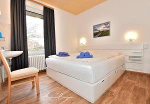 ボルクムにあるHaus-Herrmann-2の白いベッドルーム(ベッド1台、椅子付)