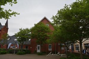 ein rotes Backsteingebäude mit Bäumen davor in der Unterkunft Haus Herrmann 2 in Borkum