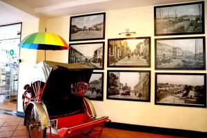 a wall of pictures on a wall with a wheelchair at Armenian Street Heritage Hotel in George Town