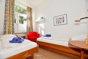 a bedroom with two beds and a red chair at Nordseehus-Whg-2 in Borkum
