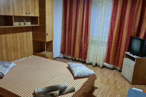 1 dormitorio con 1 cama, TV y cortinas en Colentina Residence, en Bucarest 2 fotos más
