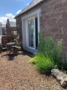 a patio with a table and chairs and a window at The Grey Cottage in Blackford
