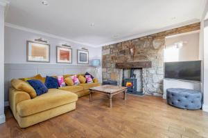 a living room with a couch and a fireplace at East Cottage * Wood Burning Hot Tub * Garden in St. Andrews