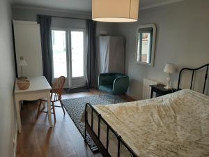 een slaapkamer met een bed, een bureau en een stoel bij Maison Bleue in Montagne