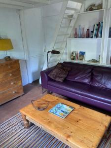sala de estar con sofá púrpura y mesa de centro de madera en Het Duinhuisje, en Goedereede