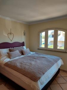 ein Schlafzimmer mit einem großen Bett und zwei Fenstern in der Unterkunft Chaminés 11 in Carvoeiro