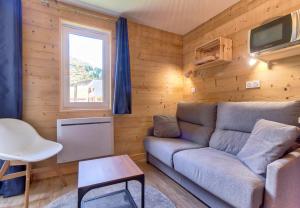 ein Wohnzimmer mit einem Sofa und einem TV in der Unterkunft Detente au pied des pistes en famille in Génos