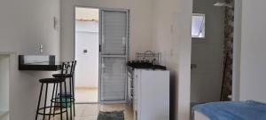 uma cozinha branca com um frigorífico e uma janela em Pousada Village Maitinga - suítes em Bertioga