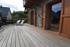 a wooden deck with two chairs sitting on it at VAUJANYLOCATIONS - Chalet de la Cîme in Vaujany